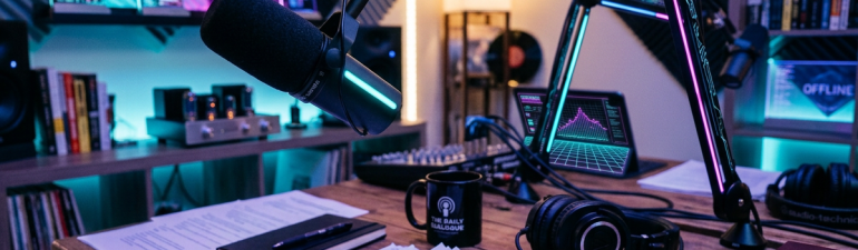 Podcast host seated beside microphones and recording equipment
